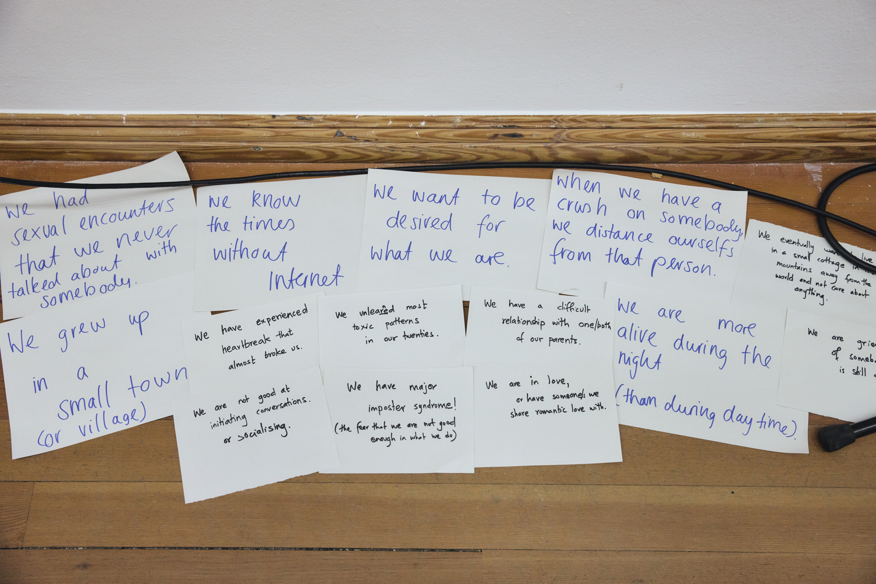 Eine Sammlung von Zetteln auf dem Boden, auf denen englische Wörter und Sätze stehen, wie z.B.: Wir sind verletzlich, Wir kennen die Welt ohne Internet etc.